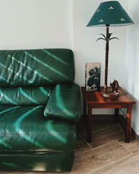 a green leather couch next to a wooden table