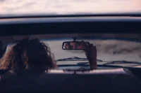 a woman in a car taking a picture in the rear view mirror