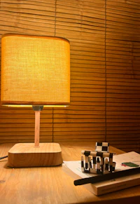 a wooden table lamp with a yellow shade on it